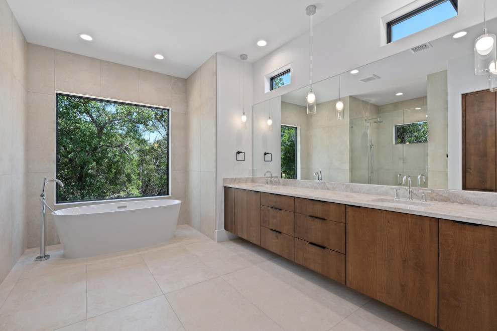 Example of a large transitional master beige tile double-sink freestanding bathtub design with flat-panel cabinets, brown cabinets, white walls, granite countertops, a hinged shower door, beige countertops and a built-in vanity