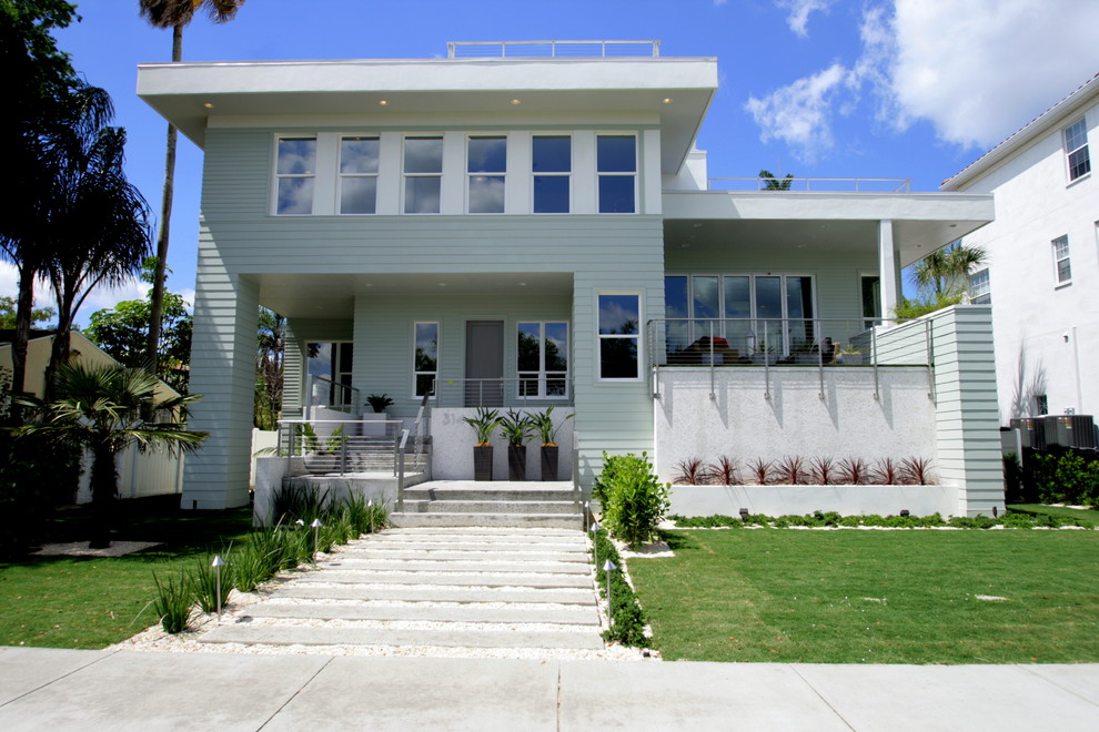 This is an example of a mid-sized modern split-level white house exterior in Tampa with mixed siding and a flat roof.