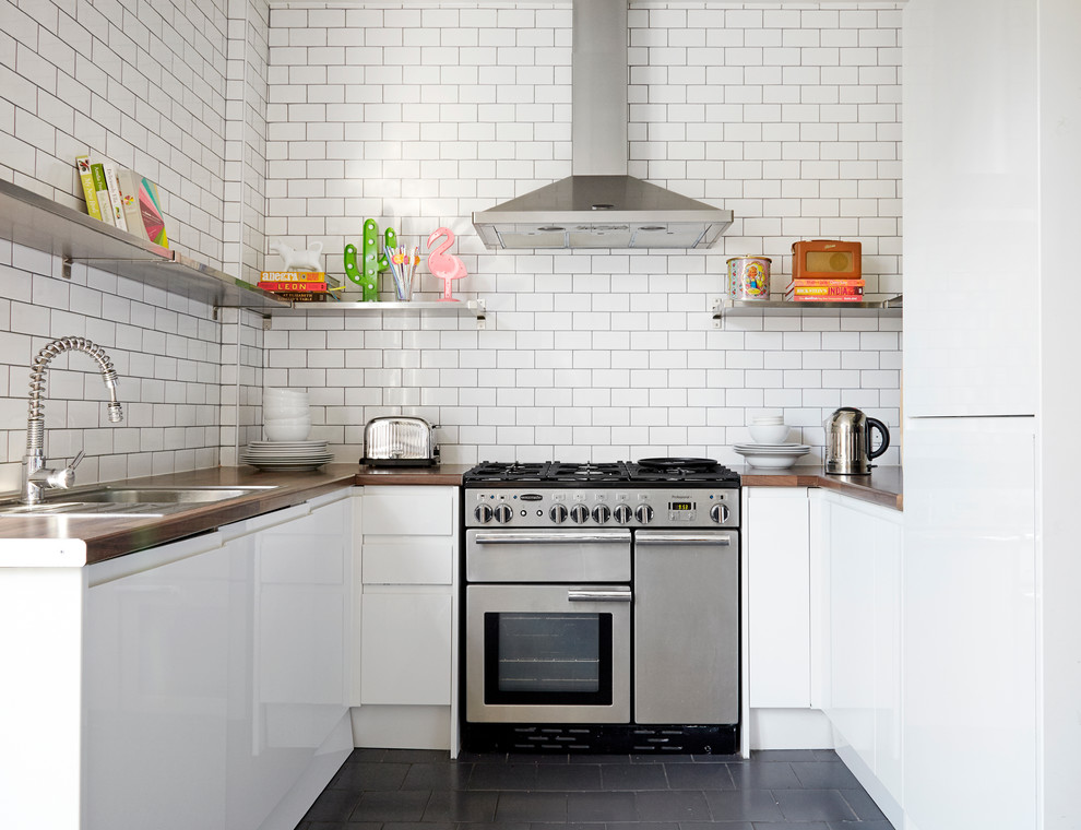 This is an example of a small contemporary u-shaped kitchen in London with a drop-in sink, flat-panel cabinets, white cabinets, laminate benchtops, white splashback, stainless steel appliances, ceramic floors, no island and subway tile splashback.