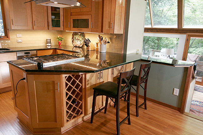 Eat-in kitchen - small transitional l-shaped porcelain tile eat-in kitchen idea with shaker cabinets, light wood cabinets, granite countertops, beige backsplash, glass tile backsplash, stainless steel appliances and a peninsula