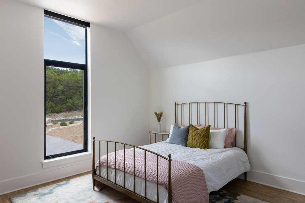 Scandi guest bedroom in Austin with white walls, light hardwood flooring and brown floors.
