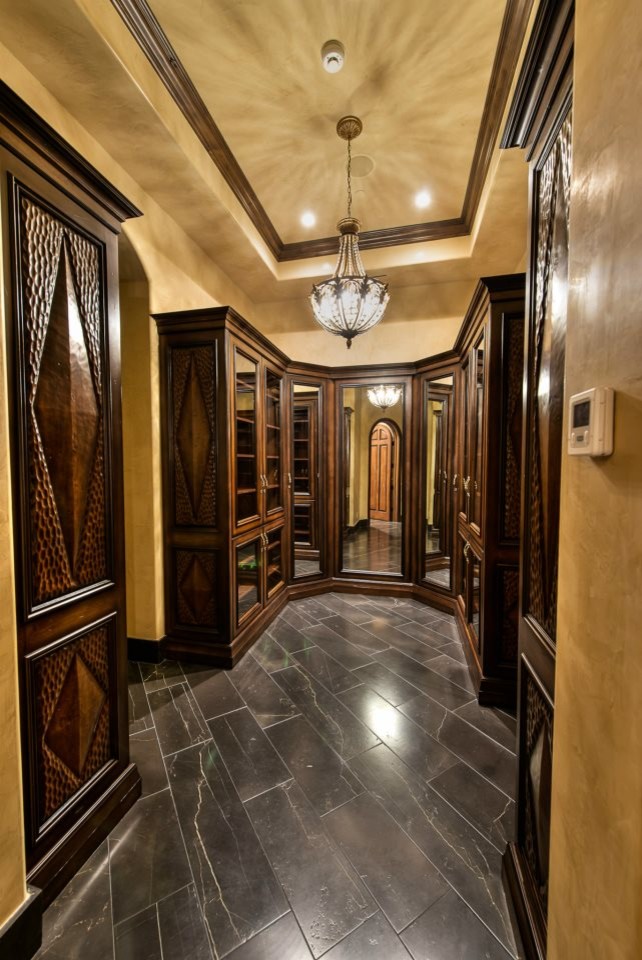 Design ideas for a mid-sized traditional men's walk-in wardrobe in Phoenix with raised-panel cabinets, medium wood cabinets and slate floors.