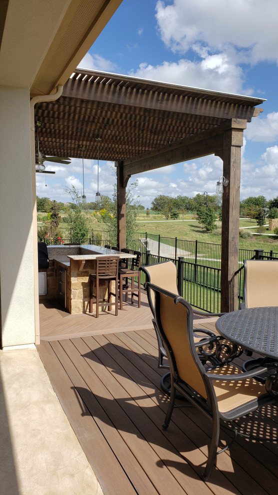 This is an example of a large bohemian back metal railing terrace in Austin with an outdoor kitchen and a pergola.