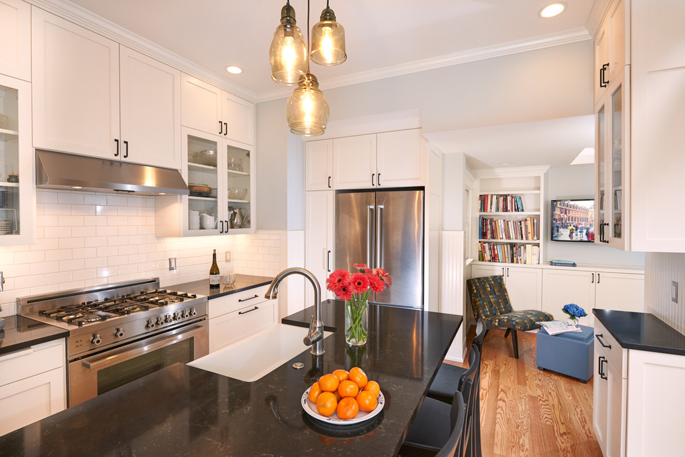 Mid-sized traditional galley separate kitchen in Seattle with a farmhouse sink, shaker cabinets, white cabinets, quartz benchtops, white splashback, subway tile splashback, stainless steel appliances, light hardwood floors, with island and yellow floor.