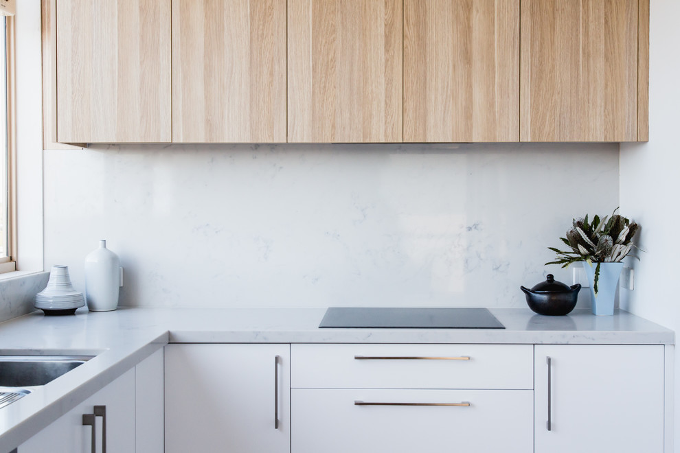This is an example of a small contemporary u-shaped separate kitchen in Melbourne with an undermount sink, white cabinets, marble benchtops, white splashback, stone tile splashback and no island.