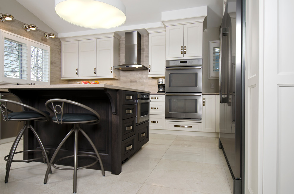 Transitional u-shaped limestone floor eat-in kitchen photo with an undermount sink, raised-panel cabinets, gray cabinets, quartz countertops, beige backsplash, stone tile backsplash, stainless steel appliances and an island