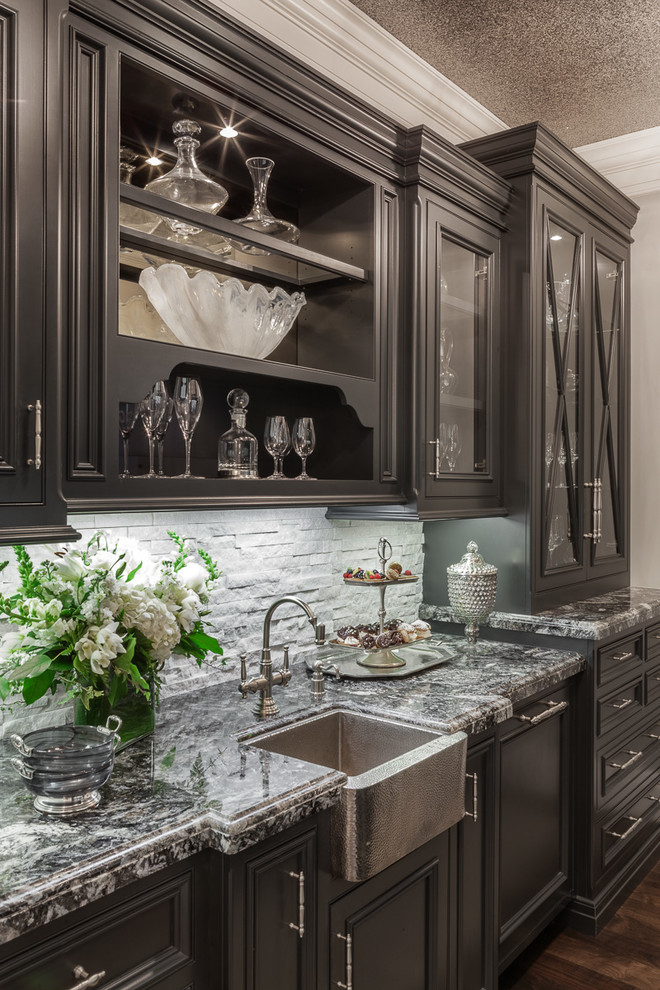 Mid-sized traditional single-wall wet bar in San Francisco with an undermount sink, glass-front cabinets, brown cabinets, granite benchtops, grey splashback, stone tile splashback, dark hardwood floors and brown floor.
