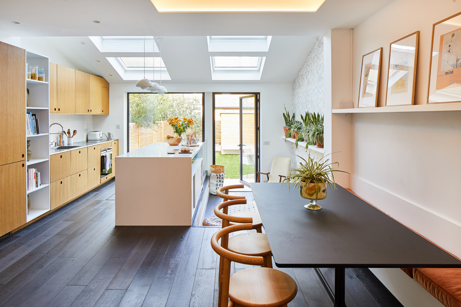 Photo of a mid-sized transitional kitchen/dining combo in London with white walls, dark hardwood floors, no fireplace and black floor.