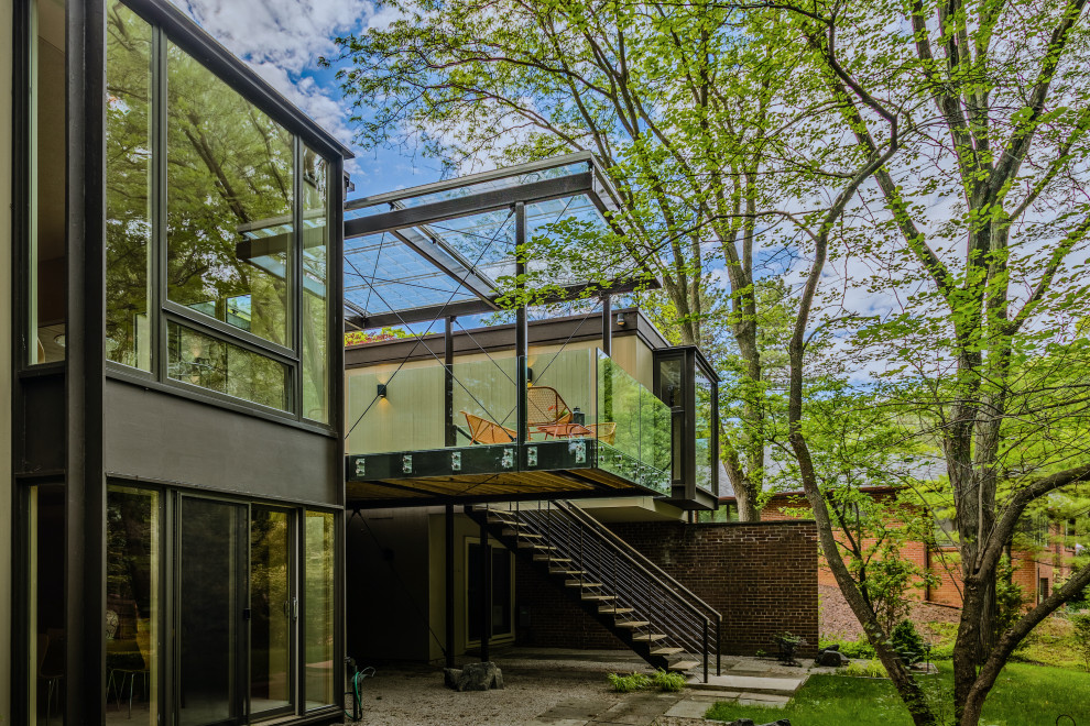 Photo of a small midcentury backyard and first floor deck in Detroit with glass railing.