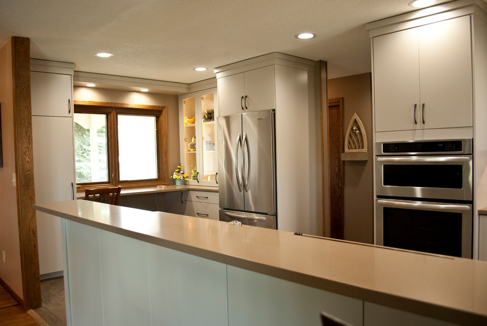 Example of a mid-sized transitional u-shaped eat-in kitchen design with an undermount sink, flat-panel cabinets, gray cabinets, brown backsplash, wood backsplash, stainless steel appliances and a peninsula