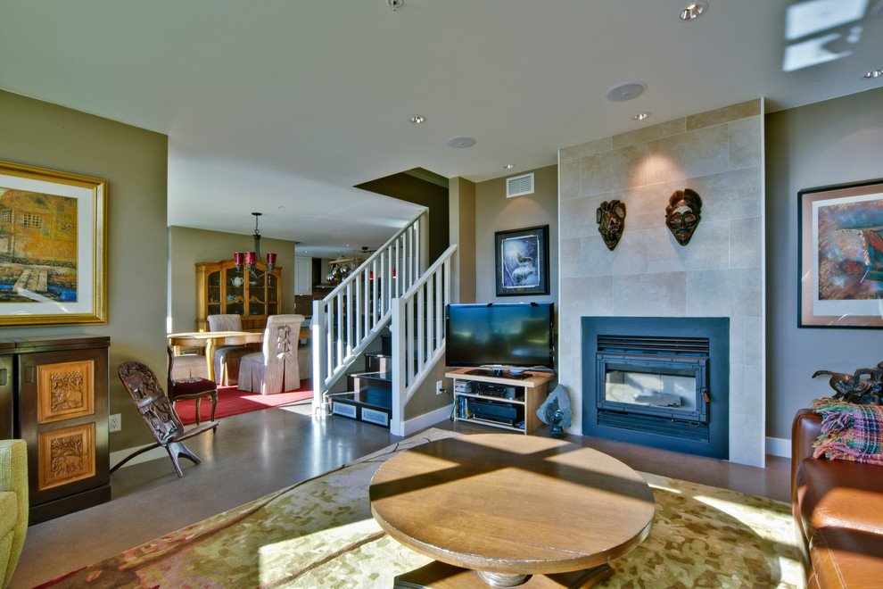 Photo of a mid-sized transitional enclosed living room in Vancouver with beige walls, concrete floors, a standard fireplace, a tile fireplace surround and a freestanding tv.