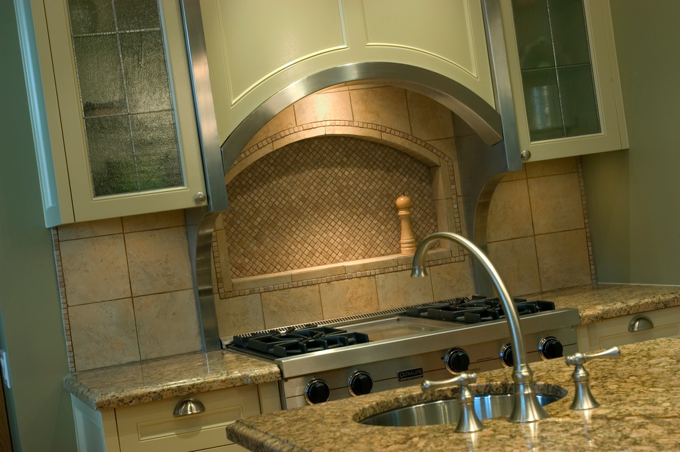 Example of a large transitional l-shaped porcelain tile enclosed kitchen design with an undermount sink, shaker cabinets, granite countertops, beige backsplash, mosaic tile backsplash, stainless steel appliances, an island, beige countertops and beige cabinets