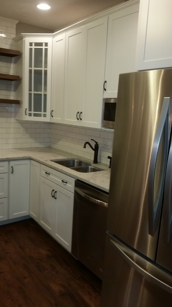 Inspiration for a mid-sized transitional u-shaped dark wood floor home design remodel in Cincinnati with an undermount sink, flat-panel cabinets, white cabinets, quartz countertops, white backsplash, subway tile backsplash, stainless steel appliances and a peninsula