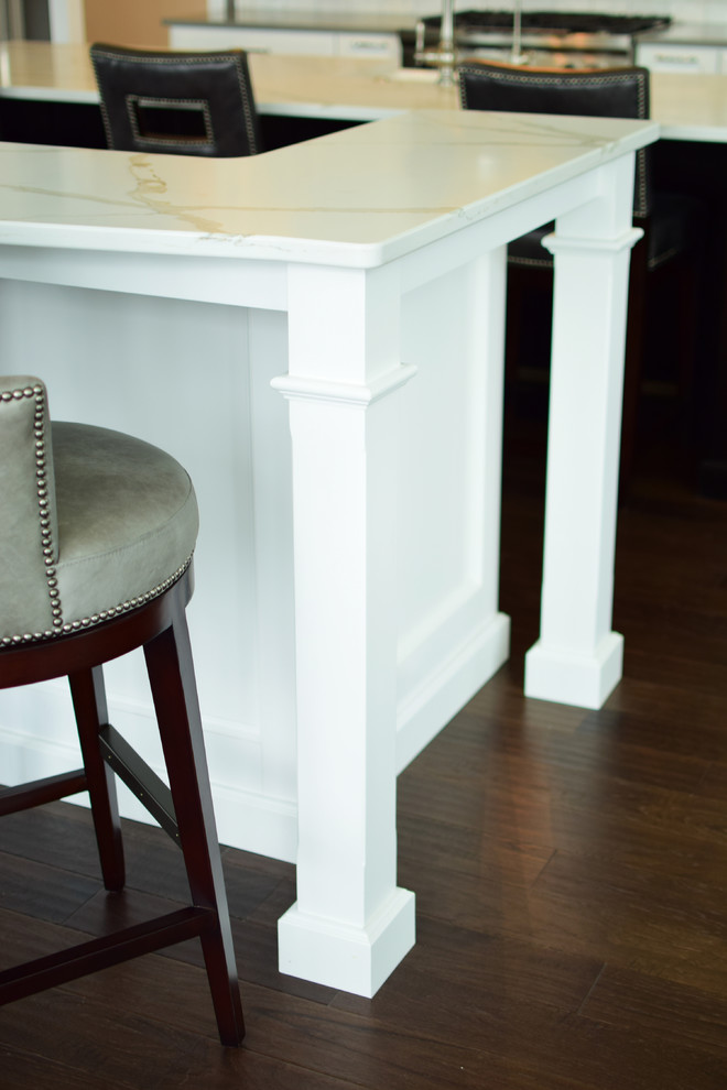 Inspiration for a large transitional l-shaped medium tone wood floor and brown floor eat-in kitchen remodel with a farmhouse sink, shaker cabinets, white cabinets, quartz countertops, white backsplash, marble backsplash, stainless steel appliances and two islands