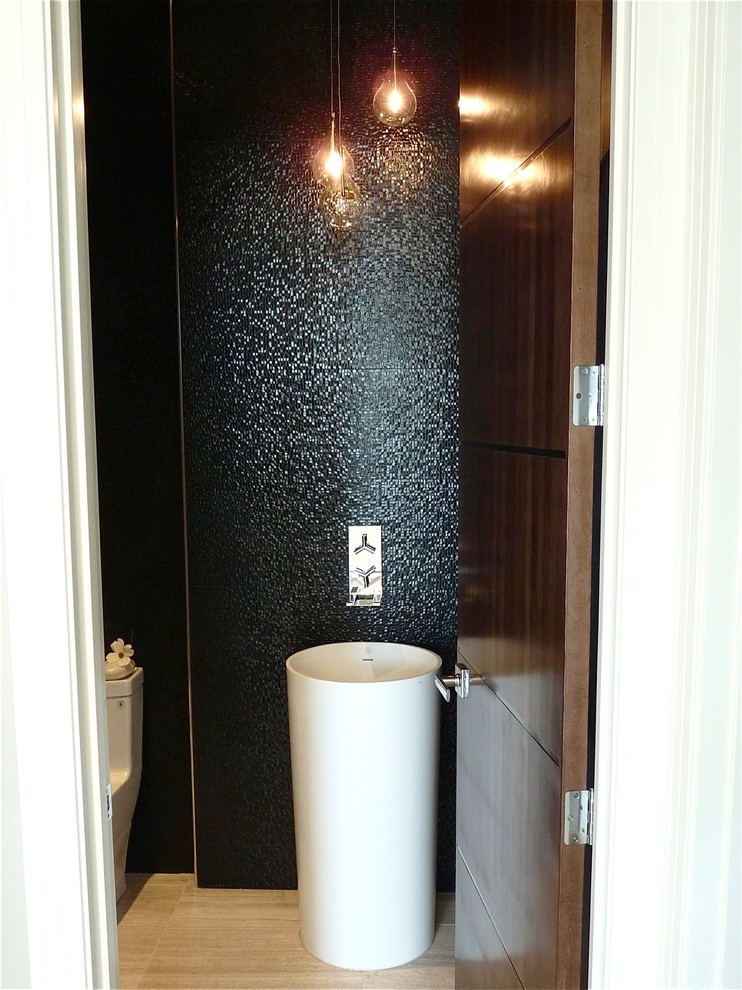 This is an example of a small modern powder room in Other with a pedestal sink, a one-piece toilet, black tile, black walls and porcelain floors.