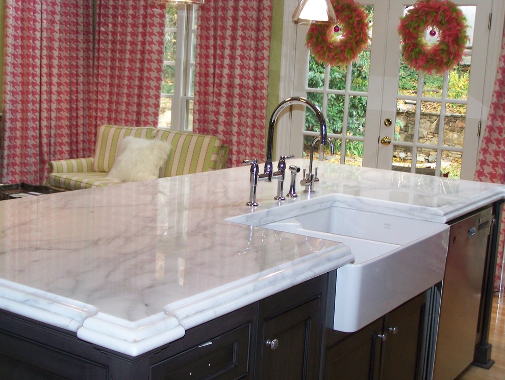 Mid-sized transitional single-wall light wood floor and beige floor enclosed kitchen photo in Raleigh with a farmhouse sink, raised-panel cabinets, black cabinets, laminate countertops, stainless steel appliances and an island