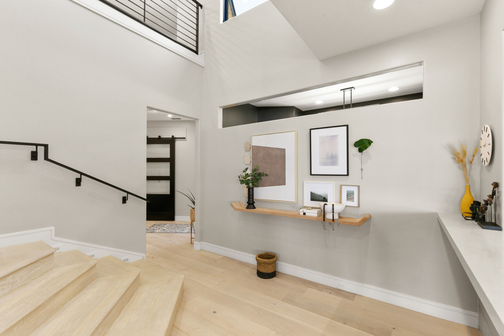 Photo of a large beach style hallway in Dallas with grey walls and light hardwood floors.