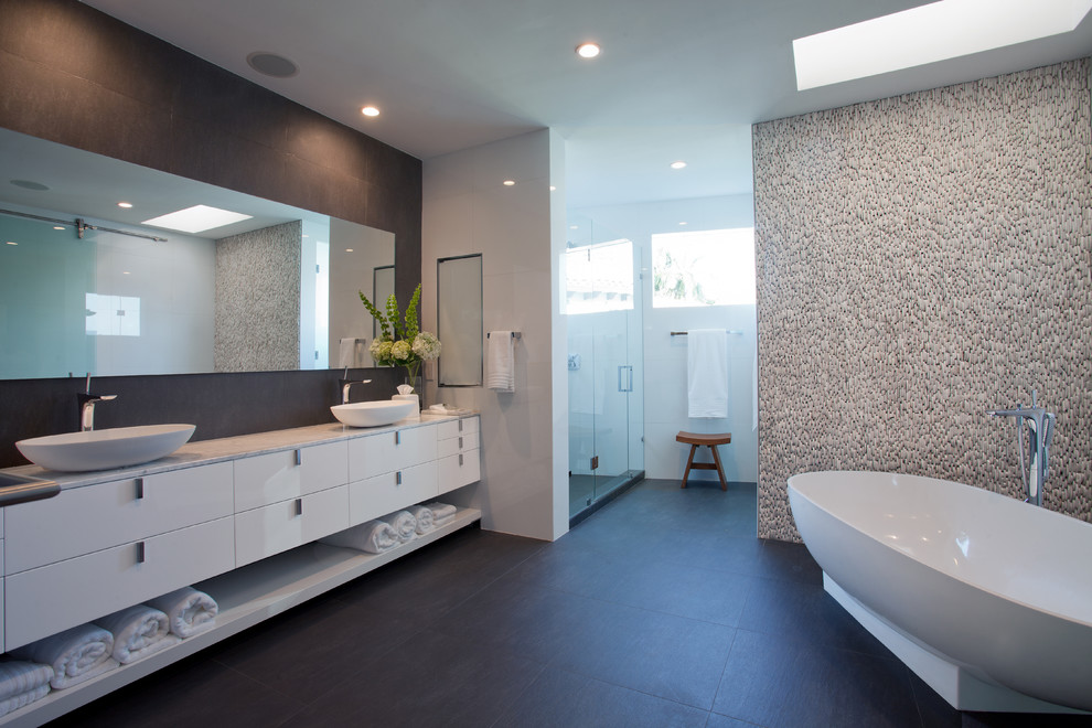 Inspiration for a large contemporary master bathroom in Miami with flat-panel cabinets, white cabinets, a freestanding tub, a corner shower, stone tile, white walls, dark hardwood floors, a vessel sink, marble benchtops, brown floor and a hinged shower door.