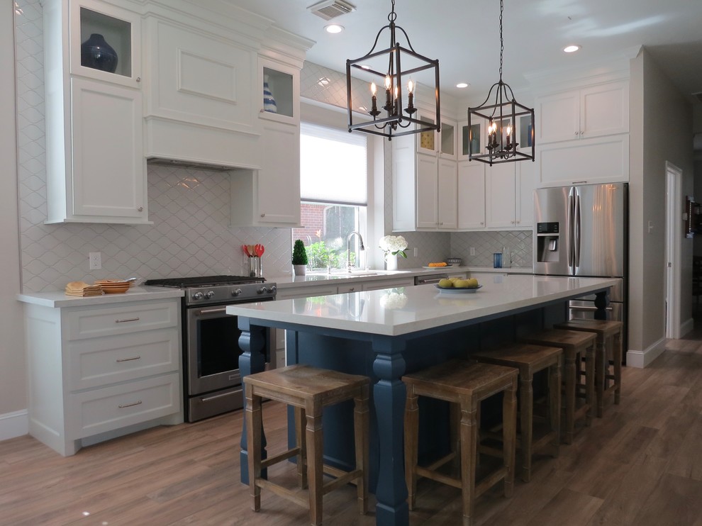 Mid-sized transitional l-shaped kitchen in Houston with an undermount sink, shaker cabinets, white cabinets, quartz benchtops, grey splashback, ceramic splashback, stainless steel appliances, porcelain floors, with island, brown floor and white benchtop.