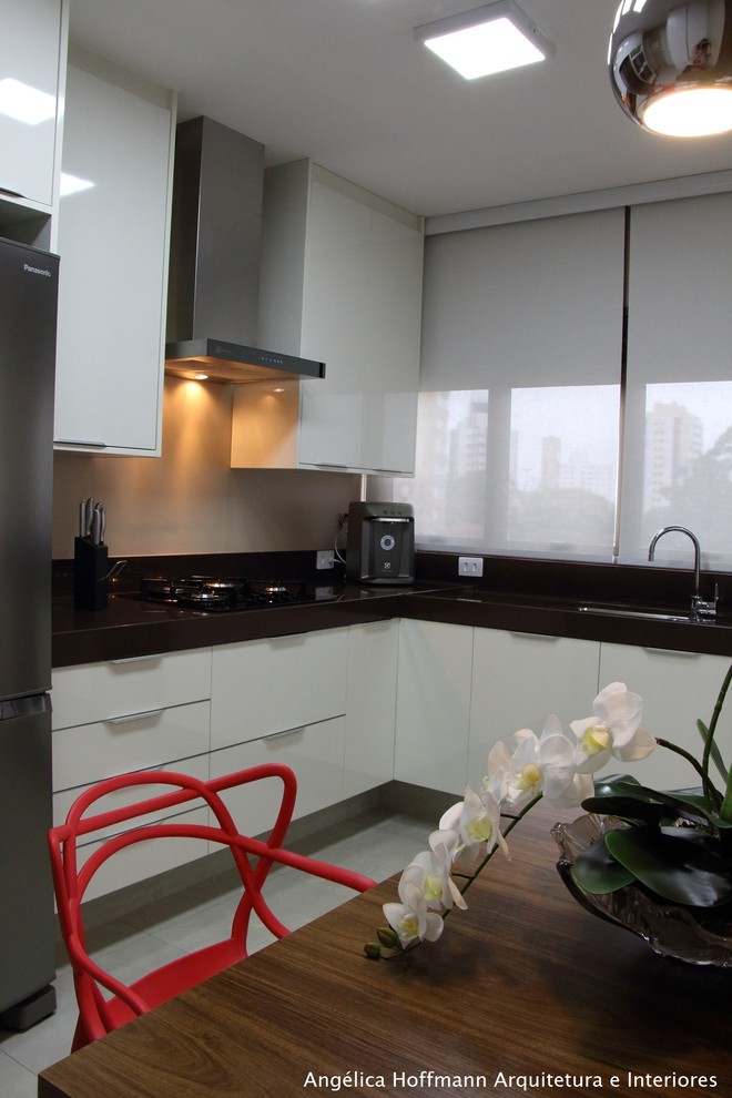 Example of a mid-sized trendy u-shaped dark wood floor and gray floor eat-in kitchen design with a drop-in sink, flat-panel cabinets, white cabinets, granite countertops, brown backsplash, window backsplash and stainless steel appliances