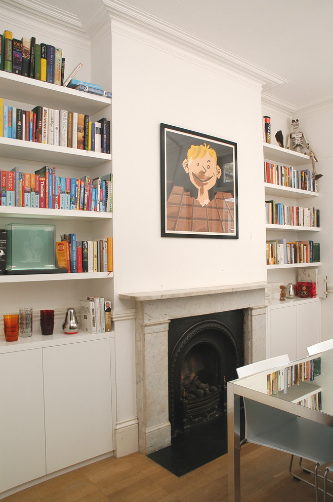 Photo of a medium sized classic enclosed dining room in London with white walls, medium hardwood flooring, a standard fireplace and a stone fireplace surround.