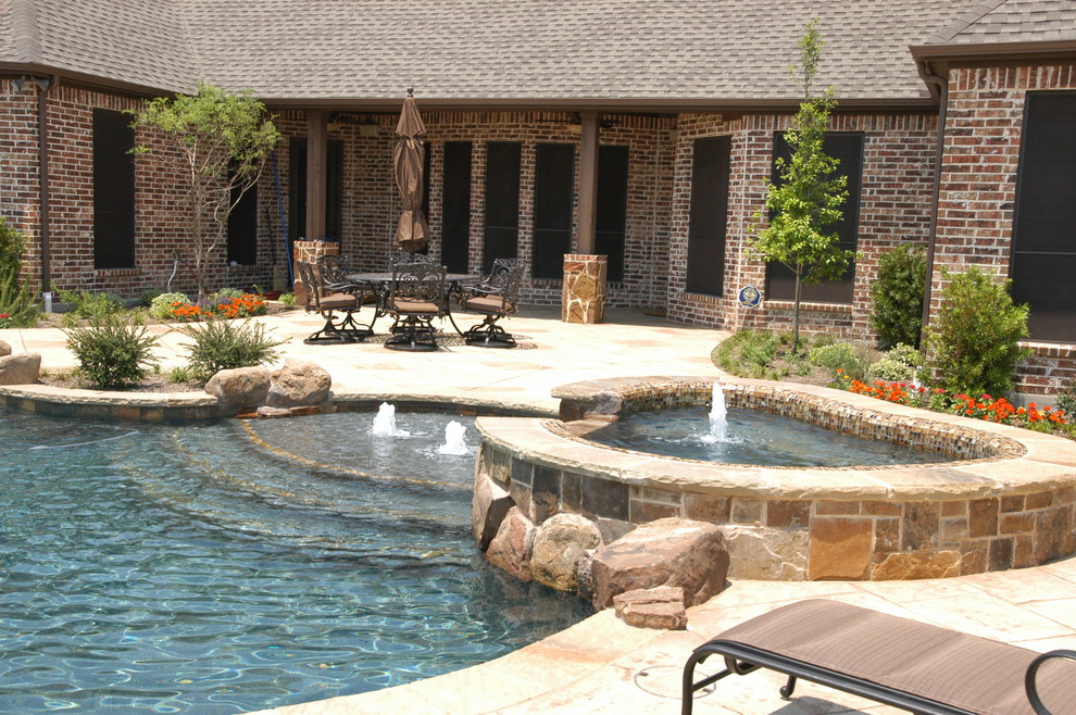 Inspiration for a large mediterranean backyard custom-shaped natural pool in Dallas with a hot tub and natural stone pavers.