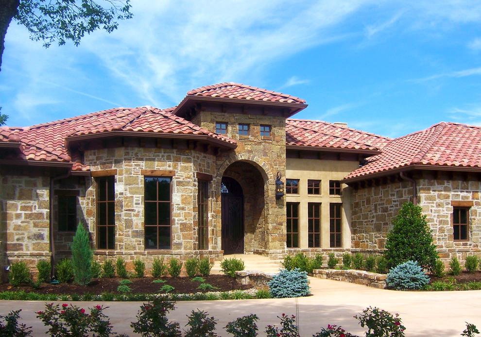 This is an example of a large mediterranean two-storey beige exterior in Oklahoma City with stone veneer.