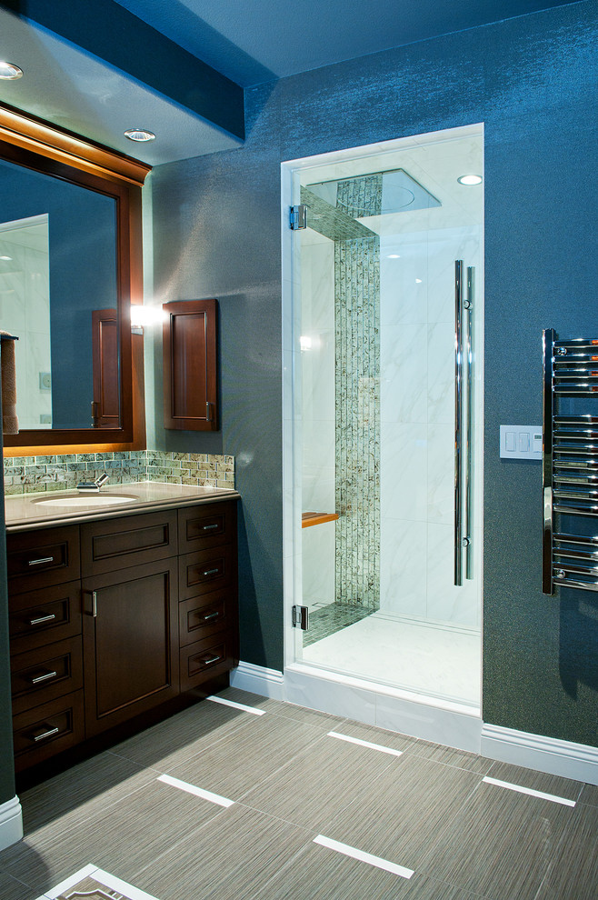 Design ideas for a large transitional bathroom in Las Vegas with recessed-panel cabinets, medium wood cabinets, an undermount sink, engineered quartz benchtops, a drop-in tub, a one-piece toilet, gray tile, glass sheet wall, blue walls, porcelain floors and with a sauna.