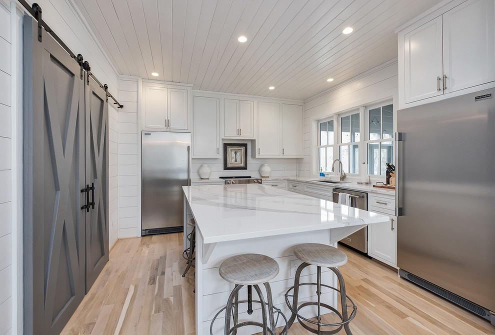 Inspiration for a transitional l-shaped light wood floor and beige floor kitchen remodel in Birmingham with an undermount sink, recessed-panel cabinets, white cabinets, stainless steel appliances, an island and white countertops