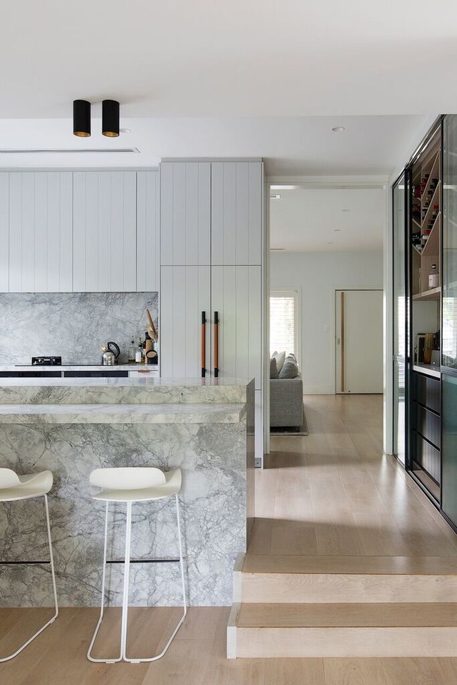 Inspiration for a beach style u-shaped kitchen in Sydney with grey splashback, panelled appliances, light hardwood floors, a peninsula, beige floor, grey benchtop and grey cabinets.