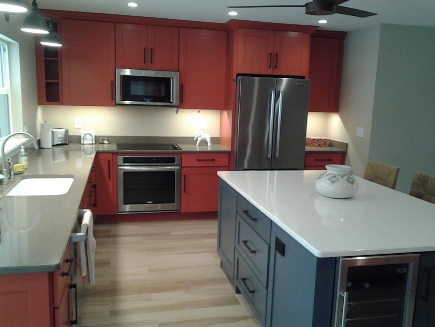 Photo of a mid-sized contemporary u-shaped eat-in kitchen in Tampa with an undermount sink, shaker cabinets, orange cabinets, solid surface benchtops, stainless steel appliances, vinyl floors and with island.