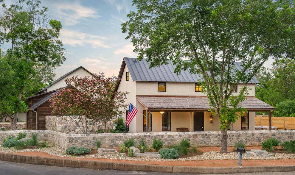 This is an example of a mid-sized country two-storey stucco beige exterior in Austin.