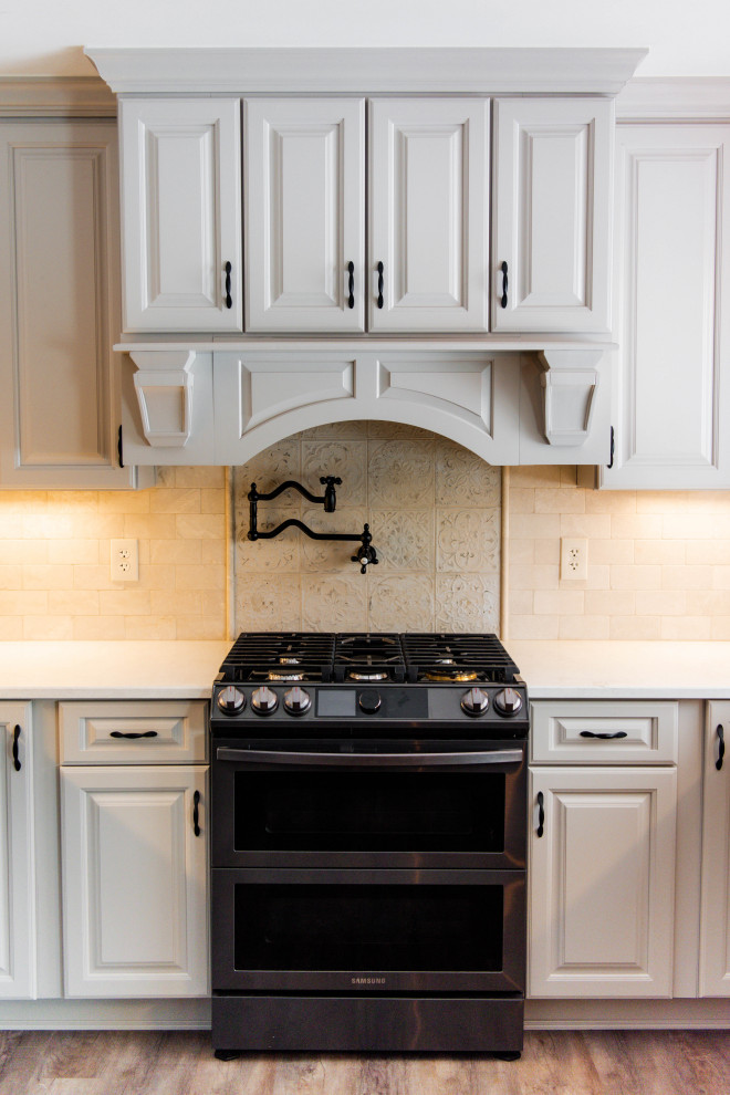 Bild på ett stort medelhavsstil vit vitt kök, med en rustik diskho, luckor med upphöjd panel, svarta skåp, bänkskiva i kvarts, beige stänkskydd, stänkskydd i marmor, rostfria vitvaror, laminatgolv, en köksö och brunt golv
