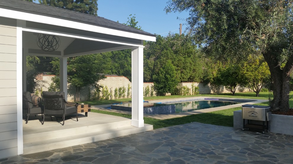 This is an example of a large modern backyard rectangular natural pool in Los Angeles with a hot tub and natural stone pavers.