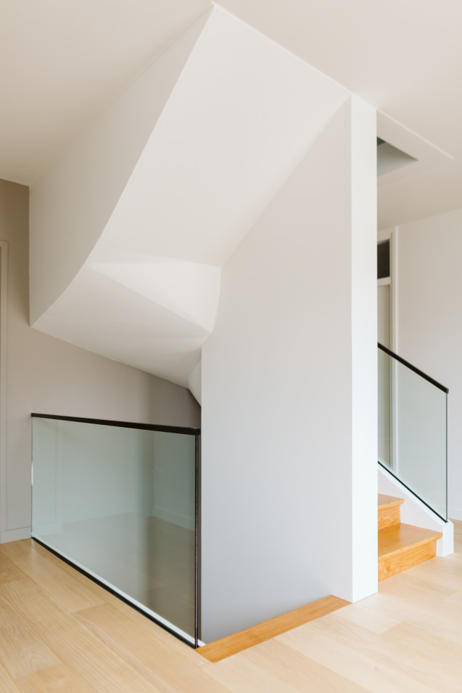 Mid-sized contemporary wood u-shaped staircase in Lille with wood risers and glass railing.