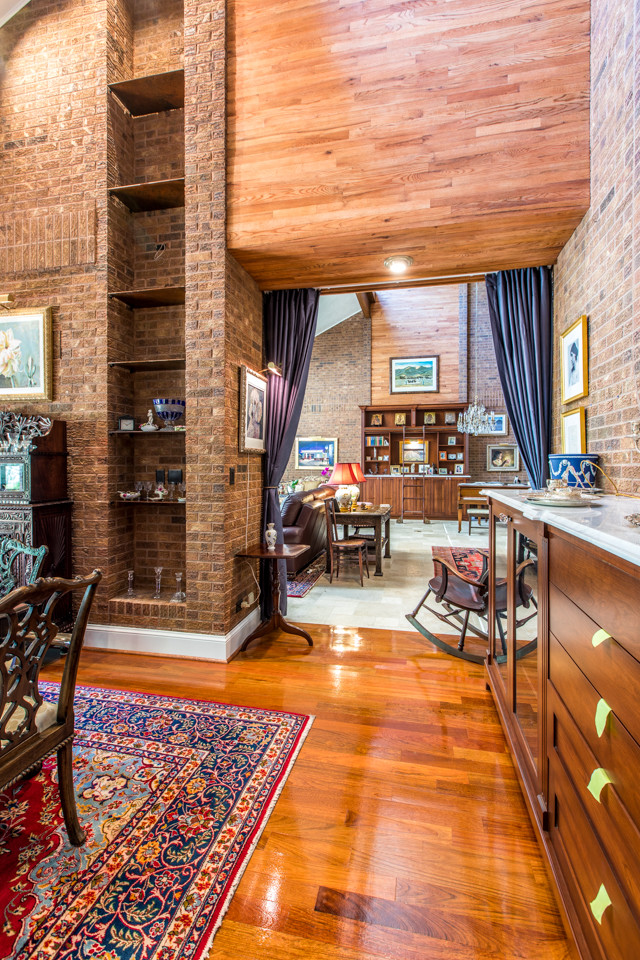Large traditional separate dining room in Denver with brown walls, medium hardwood floors, a two-sided fireplace, a brick fireplace surround and red floor.