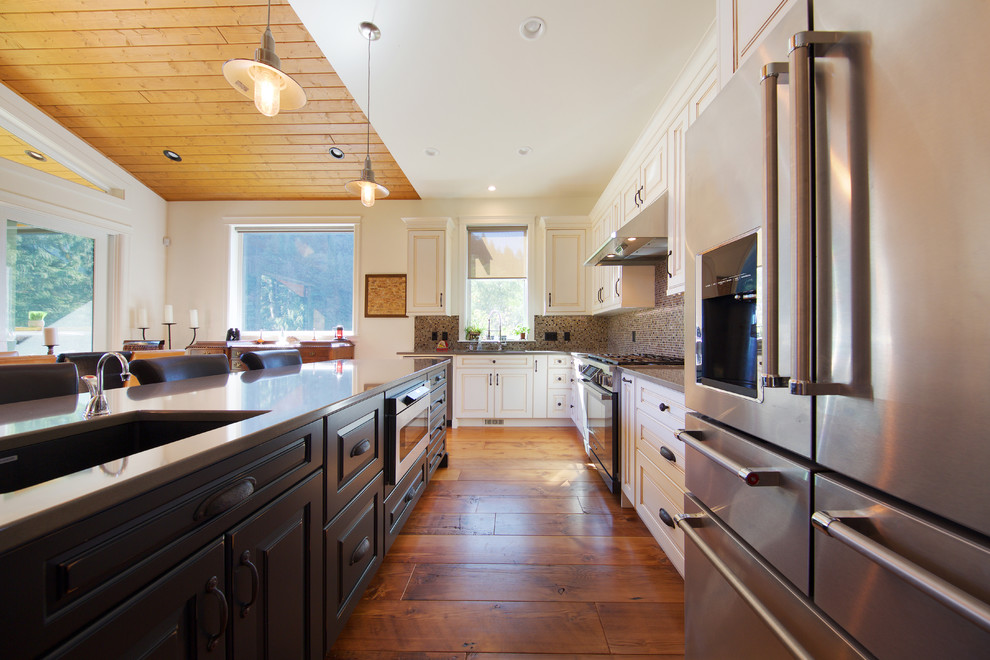 Mountain style l-shaped medium tone wood floor open concept kitchen photo in Vancouver with a double-bowl sink, louvered cabinets, distressed cabinets, multicolored backsplash, ceramic backsplash, stainless steel appliances and an island