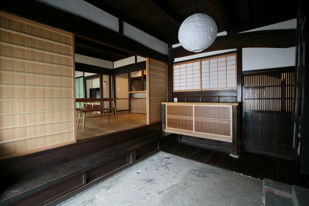 Asiatischer Eingang mit weißer Wandfarbe, brauner Haustür, grauem Boden und Holzdecke in Sonstige