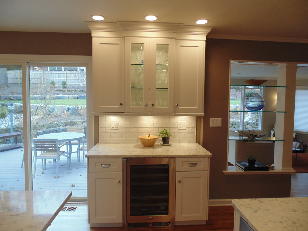 Large transitional u-shaped medium tone wood floor and brown floor eat-in kitchen photo with an undermount sink, recessed-panel cabinets, white cabinets, quartz countertops, white backsplash, subway tile backsplash, stainless steel appliances, an island and white countertops