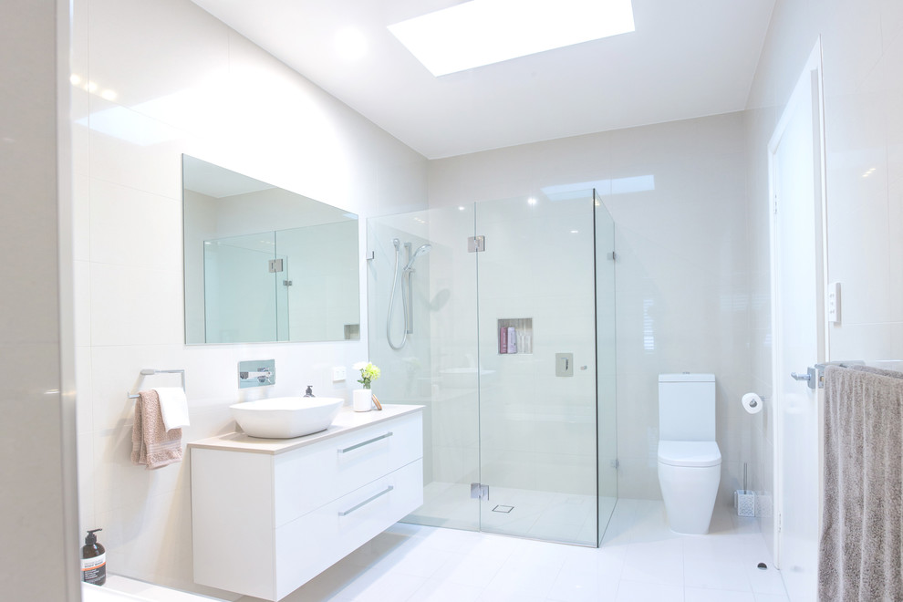 Design ideas for a mid-sized contemporary master bathroom in Central Coast with white cabinets, engineered quartz benchtops, an open shower, white tile, a vessel sink, a one-piece toilet, white walls and a hinged shower door.