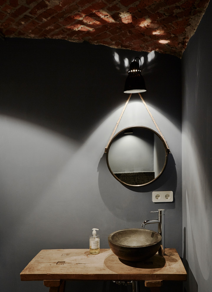 Kleines Industrial Duschbad mit grauer Wandfarbe, Kalkstein, Aufsatzwaschbecken, Waschtisch aus Holz und schwarzem Boden in Hamburg