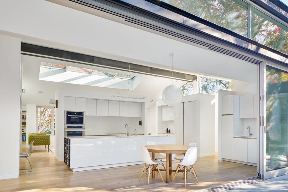 Inspiration for a mid-sized modern single-wall eat-in kitchen in San Francisco with an undermount sink, flat-panel cabinets, white cabinets, stainless steel appliances, light hardwood floors, with island, brown floor and white benchtop.