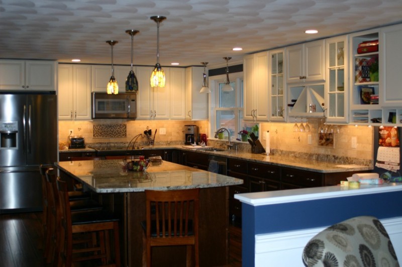 Open concept kitchen - large transitional l-shaped dark wood floor open concept kitchen idea in Providence with an undermount sink, glass-front cabinets, white cabinets, granite countertops, beige backsplash, subway tile backsplash, stainless steel appliances and an island