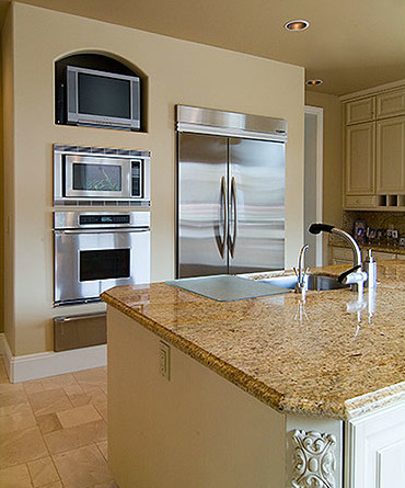 Mid-sized beach style kitchen photo with a drop-in sink, white cabinets, stainless steel appliances, an island and stone slab backsplash