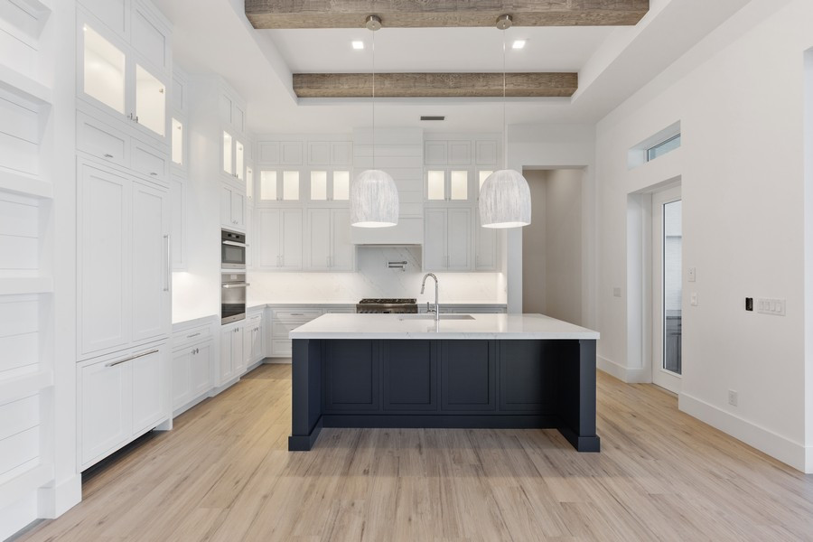 This is an example of a large transitional l-shaped open plan kitchen in Miami with shaker cabinets, white cabinets, with island, an undermount sink, marble benchtops, white splashback, marble splashback, panelled appliances, light hardwood floors, brown floor and white benchtop.