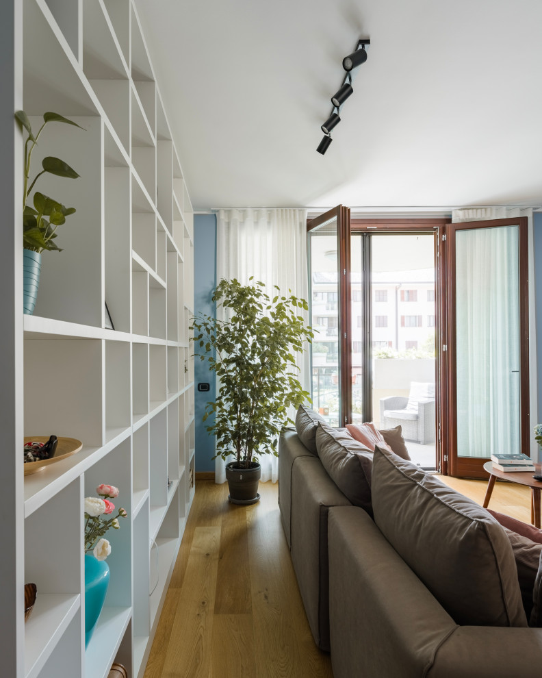 Immagine di un soggiorno contemporaneo di medie dimensioni e aperto con libreria, pareti bianche, parquet chiaro, parete attrezzata e pavimento beige