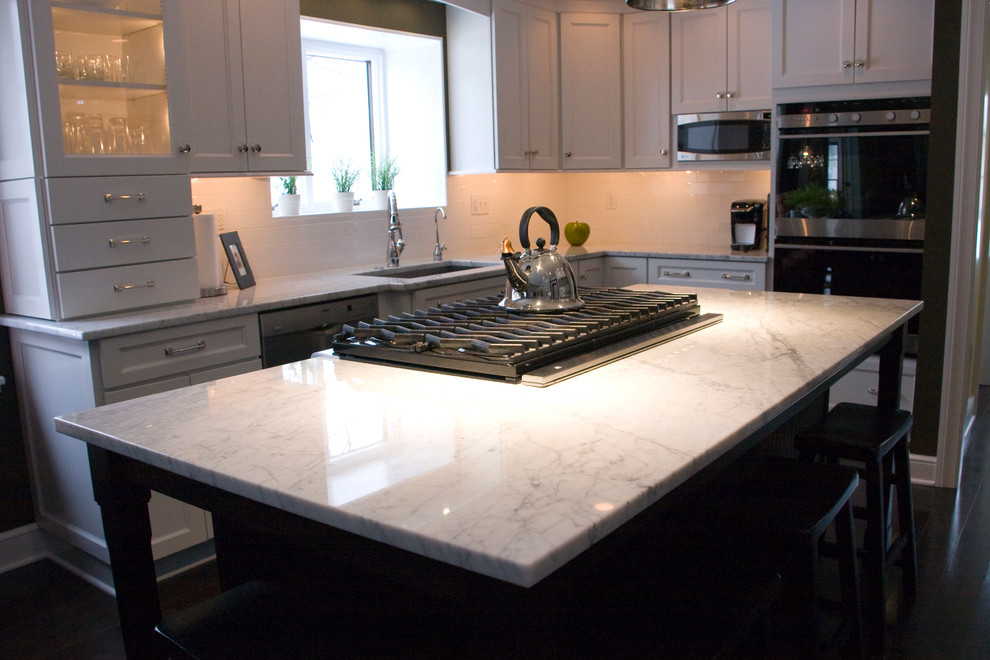 Large transitional dark wood floor kitchen photo with an undermount sink, shaker cabinets, white cabinets, marble countertops, white backsplash, subway tile backsplash, stainless steel appliances and an island