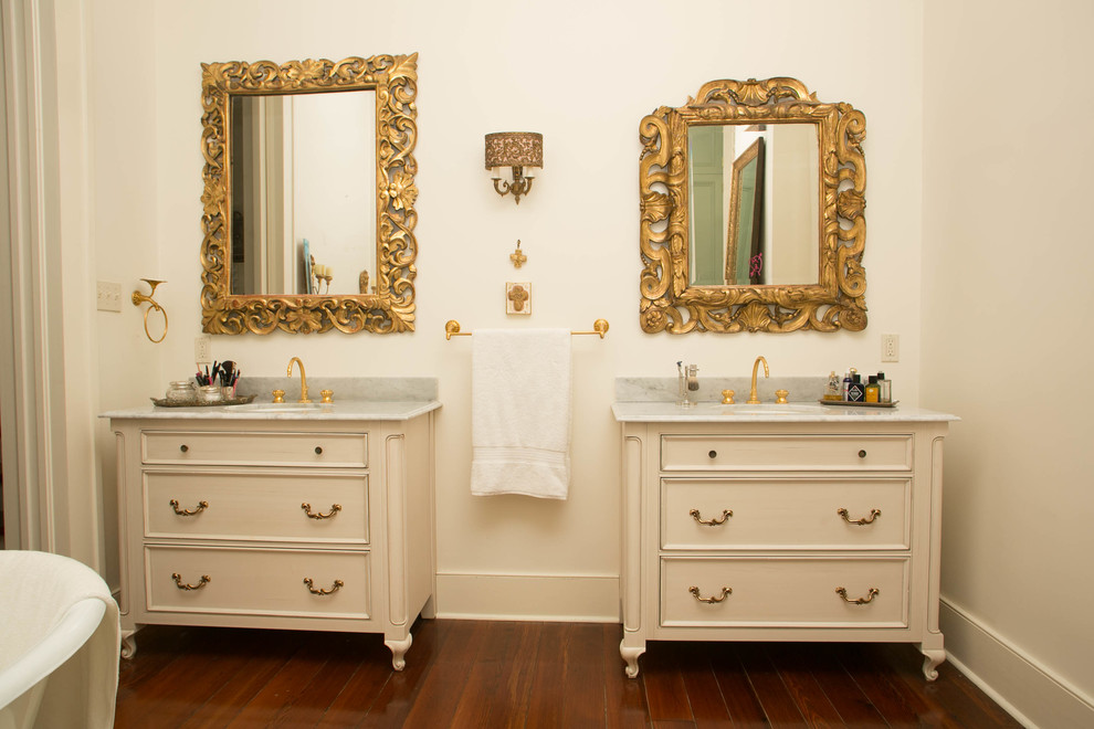 Photo of a large traditional master bathroom in New Orleans with recessed-panel cabinets, white cabinets, dark hardwood floors, an undermount sink and marble benchtops.