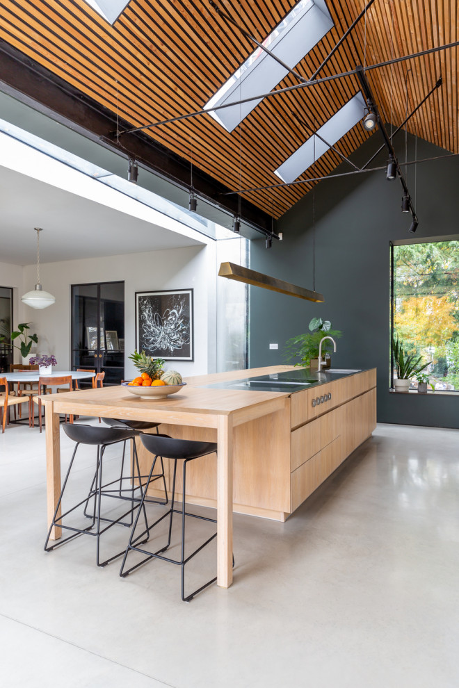 Expansive scandi open plan kitchen in London with flat-panel cabinets, white cabinets, stainless steel worktops, an island and multicoloured worktops.