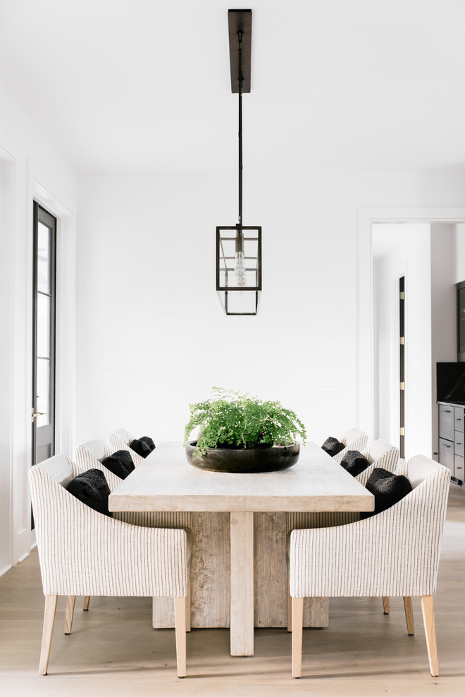 Photo of a transitional dining room in Charleston with white walls and light hardwood floors.